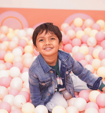 Smiling child enjoying colourful ball pit play at Mio Wooray.